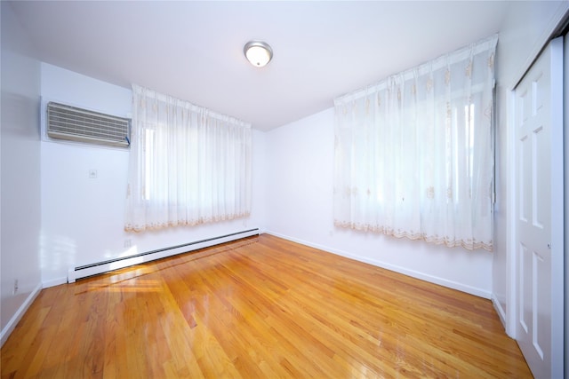 unfurnished room featuring hardwood / wood-style flooring, a baseboard radiator, and a wall mounted AC