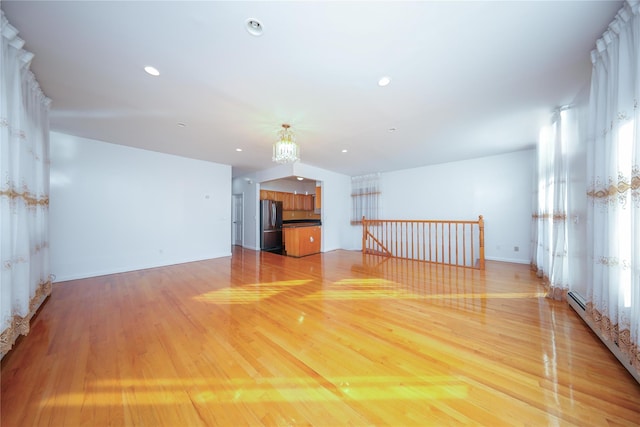 unfurnished living room with a baseboard radiator and light wood-type flooring