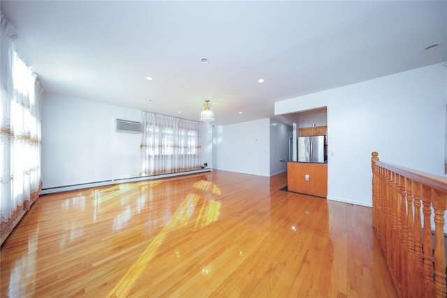 unfurnished room with baseboard heating and light hardwood / wood-style flooring