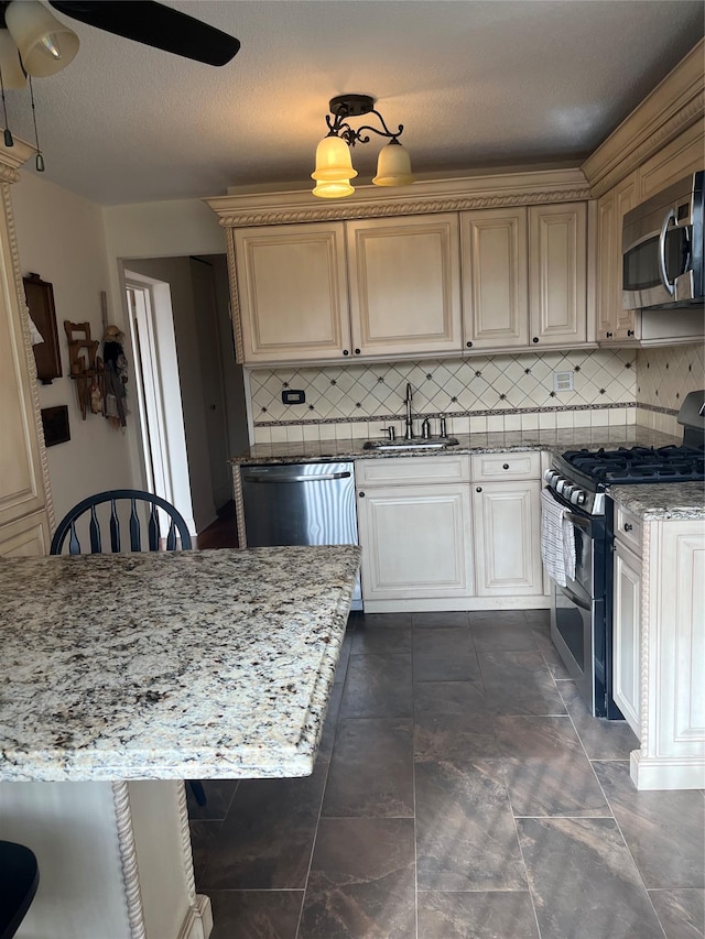 kitchen with sink, ceiling fan, stainless steel appliances, light stone counters, and tasteful backsplash