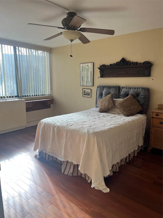 bedroom with ceiling fan, a textured ceiling, and dark hardwood / wood-style flooring