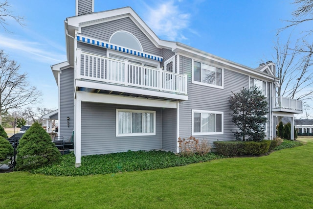 back of property featuring a lawn and a balcony