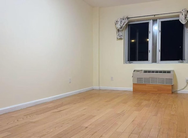 empty room featuring a wall mounted air conditioner and light hardwood / wood-style flooring