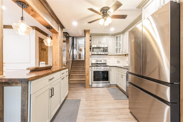 kitchen with butcher block countertops, white cabinetry, stainless steel appliances, tasteful backsplash, and decorative light fixtures