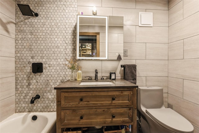 full bathroom featuring vanity, tiled shower / bath, tile walls, and toilet