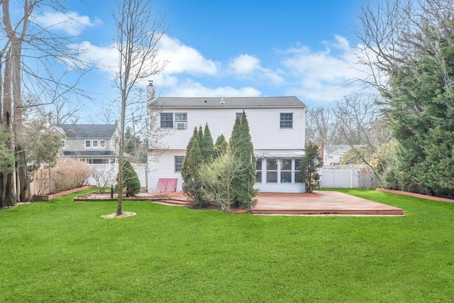 back of property featuring a wooden deck, a lawn, and a sunroom