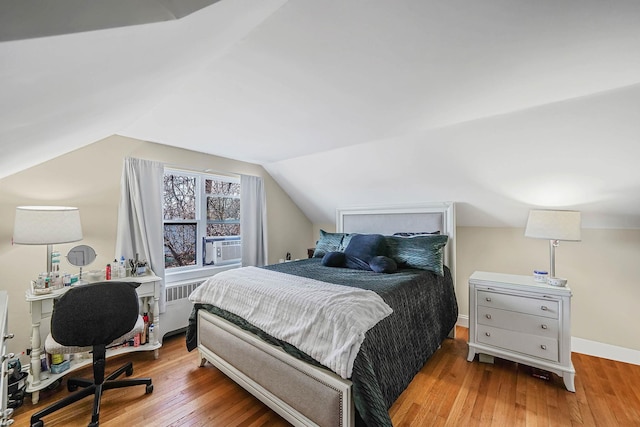 bedroom with vaulted ceiling, radiator, cooling unit, and light hardwood / wood-style floors