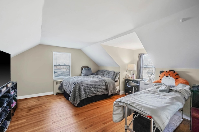 bedroom featuring multiple windows, wood-type flooring, vaulted ceiling, and radiator heating unit