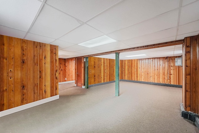 basement with carpet flooring, a drop ceiling, and wooden walls