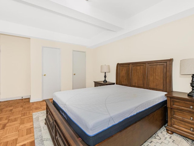 bedroom featuring beamed ceiling and light parquet flooring