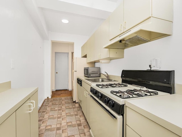 kitchen featuring white gas range, sink, and cream cabinets