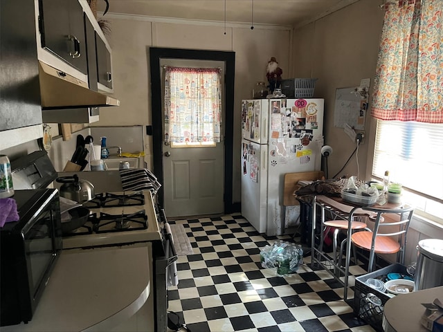 kitchen featuring crown molding, ventilation hood, range with gas stovetop, and white fridge