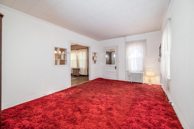 empty room featuring crown molding, carpet floors, and radiator heating unit