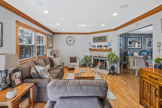 living room featuring a tiled fireplace, crown molding, and light hardwood / wood-style floors