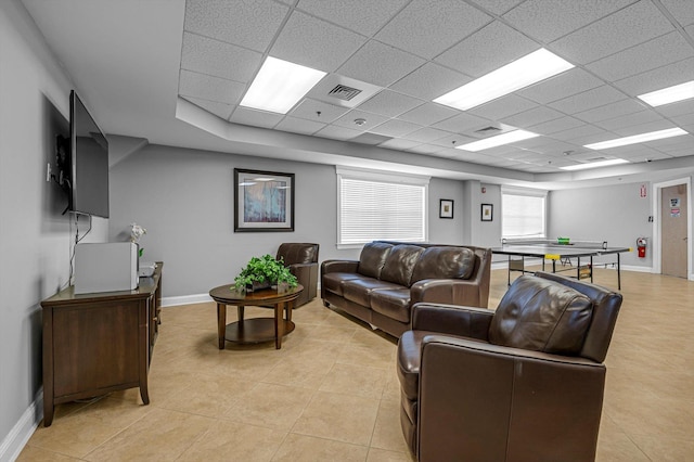 living room with a paneled ceiling and light tile patterned floors