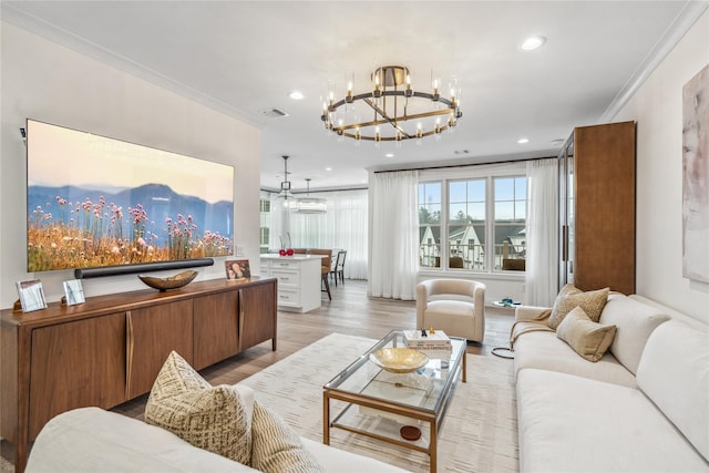 living room featuring a notable chandelier, ornamental molding, and light hardwood / wood-style floors