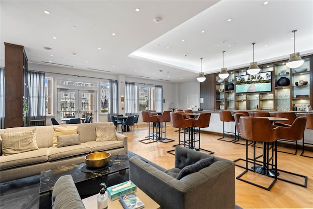 living room featuring light parquet floors, a tray ceiling, and french doors