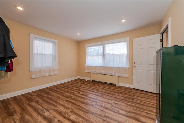 foyer entrance with hardwood / wood-style floors and radiator heating unit