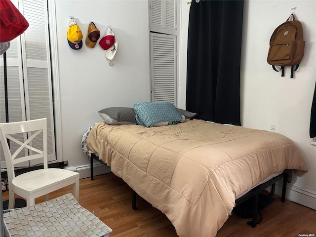 bedroom with wood-type flooring and a baseboard radiator