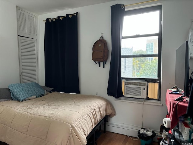 bedroom featuring hardwood / wood-style floors, baseboard heating, and cooling unit