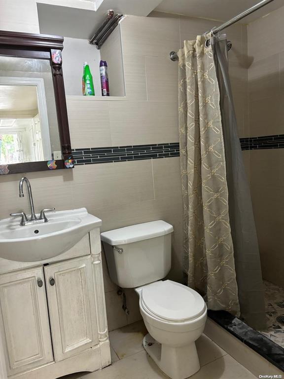 bathroom with vanity, toilet, tile patterned floors, and walk in shower