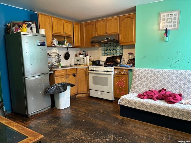 kitchen featuring backsplash, white gas stove, stainless steel fridge, and dark hardwood / wood-style flooring