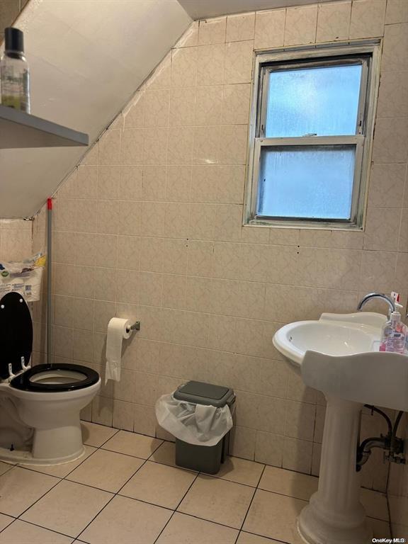 bathroom with vaulted ceiling, tile walls, tile patterned floors, and toilet