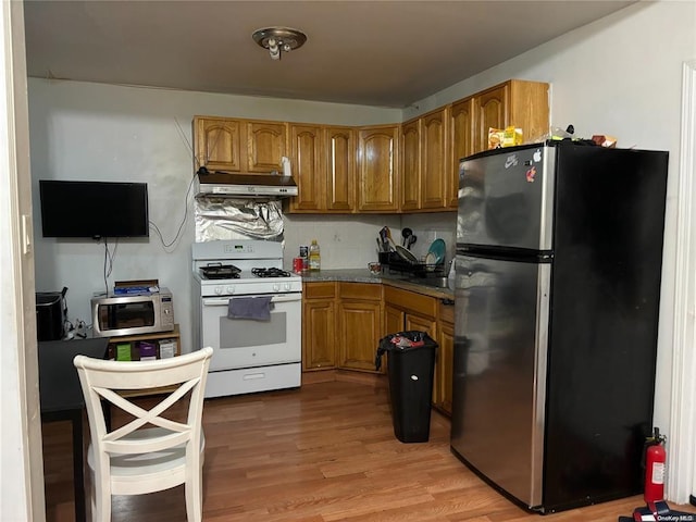 kitchen with tasteful backsplash, appliances with stainless steel finishes, and light hardwood / wood-style flooring