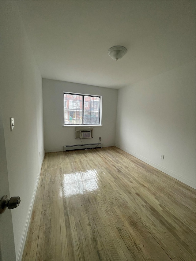 unfurnished room with a baseboard heating unit, light hardwood / wood-style flooring, and an AC wall unit