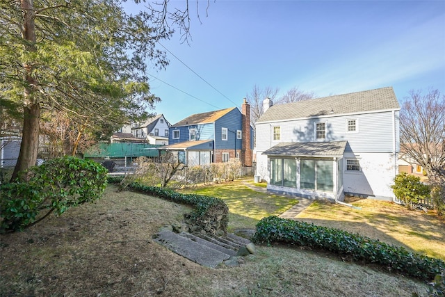 rear view of house with a sunroom and a lawn