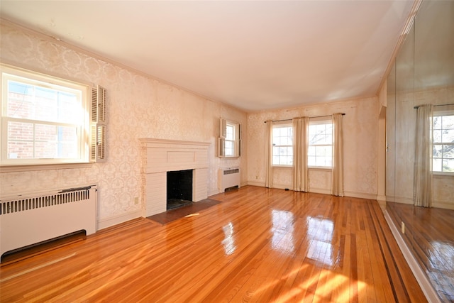 unfurnished living room featuring radiator, hardwood / wood-style flooring, and a wealth of natural light