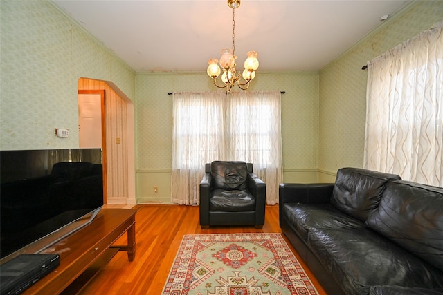 living room featuring ornamental molding, hardwood / wood-style floors, and an inviting chandelier