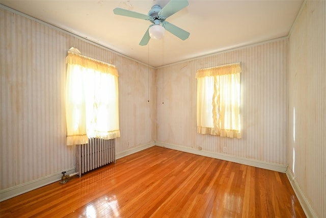 spare room featuring hardwood / wood-style floors, radiator heating unit, and ceiling fan