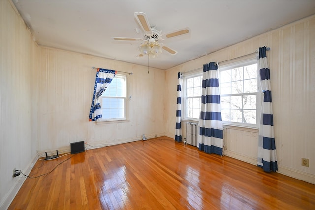 spare room with hardwood / wood-style flooring, radiator heating unit, and ceiling fan