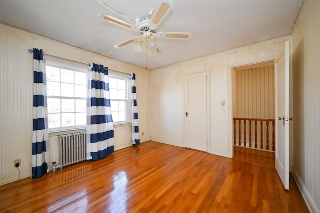 unfurnished bedroom with radiator, hardwood / wood-style floors, and ceiling fan