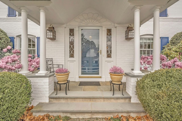 property entrance featuring brick siding and covered porch