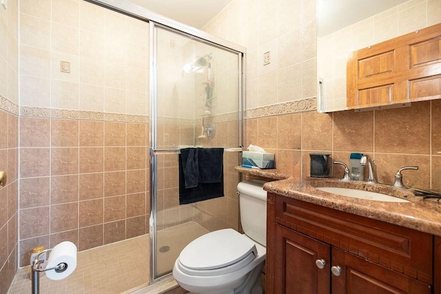 bathroom featuring tile walls, vanity, tasteful backsplash, a shower with shower door, and toilet