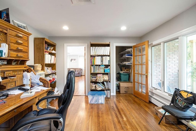 office space featuring a baseboard radiator, a wealth of natural light, and light wood-type flooring