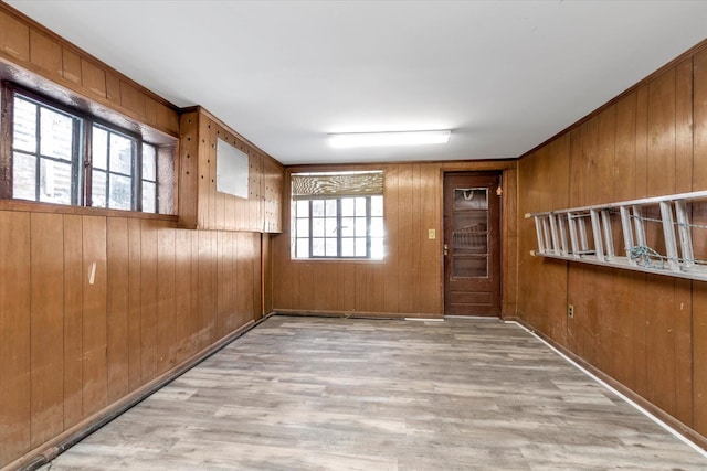 spare room featuring wooden walls and light wood-type flooring