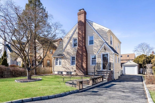 view of front facade with driveway, a garage, a chimney, fence, and an outdoor structure