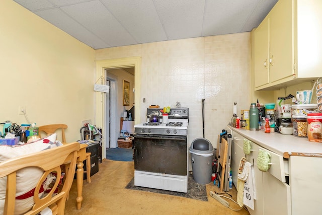 kitchen featuring light colored carpet, light countertops, and white gas range oven