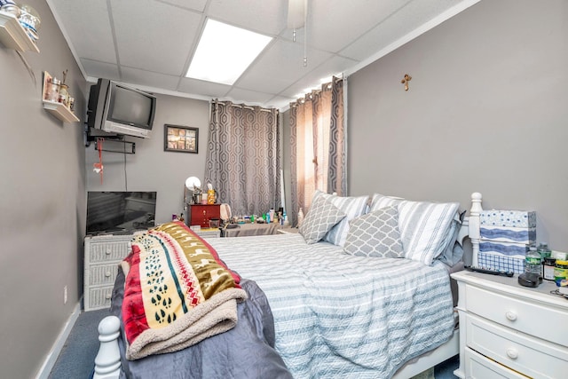 carpeted bedroom with a paneled ceiling and baseboards