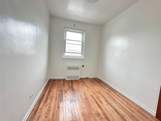 spare room featuring radiator and light wood-type flooring