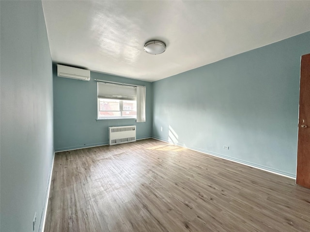 empty room with hardwood / wood-style flooring, radiator, and a wall unit AC