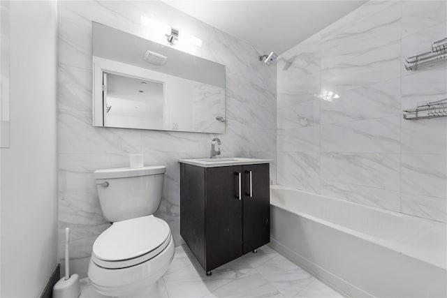 full bathroom featuring tiled shower / bath, vanity, toilet, and tile walls