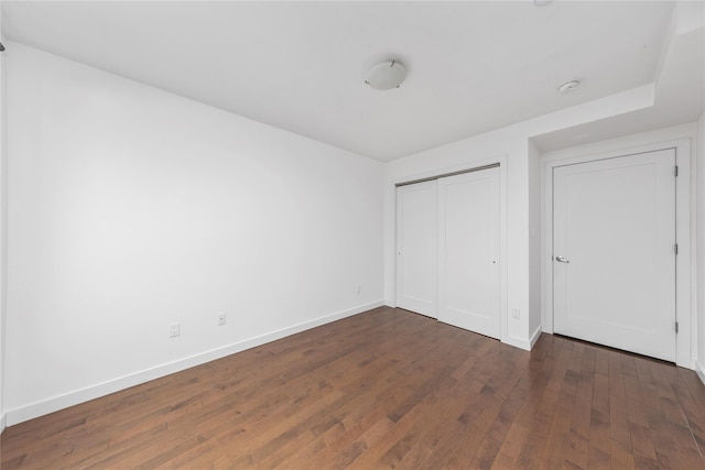 unfurnished bedroom featuring dark wood-type flooring and a closet