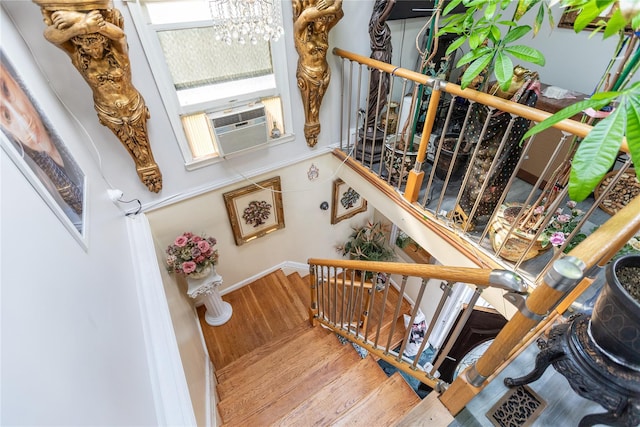 stairway with wood-type flooring, cooling unit, and a chandelier