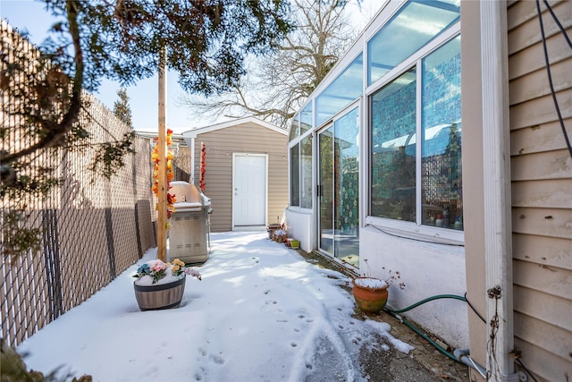 snow covered patio featuring area for grilling and a sunroom