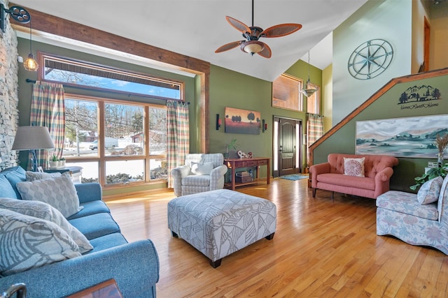 living room featuring ceiling fan, a towering ceiling, and light hardwood / wood-style flooring