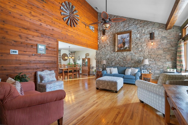 living room with ceiling fan with notable chandelier, high vaulted ceiling, light hardwood / wood-style floors, and beamed ceiling